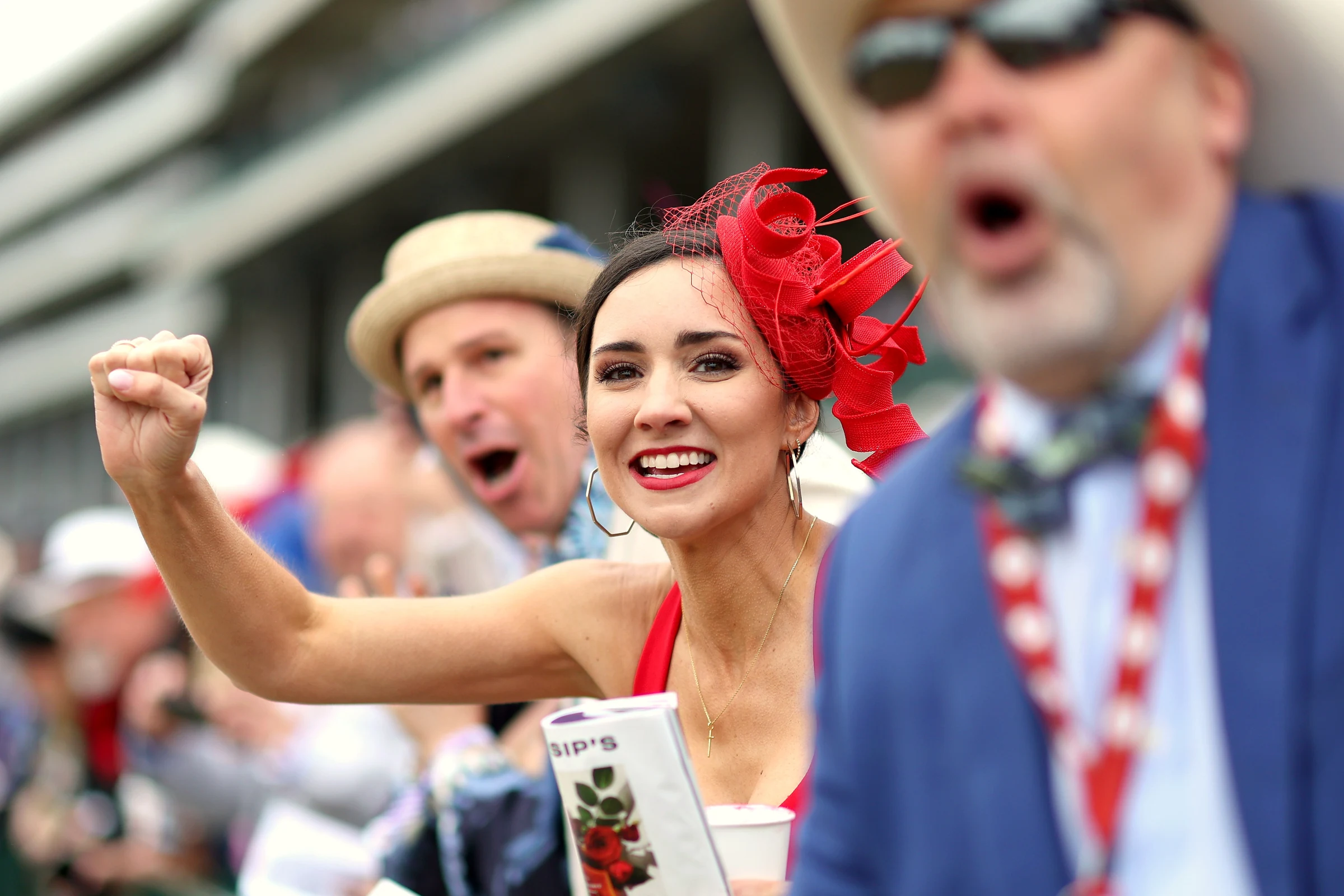 Fans in Derby hats cheering at the rail during a race